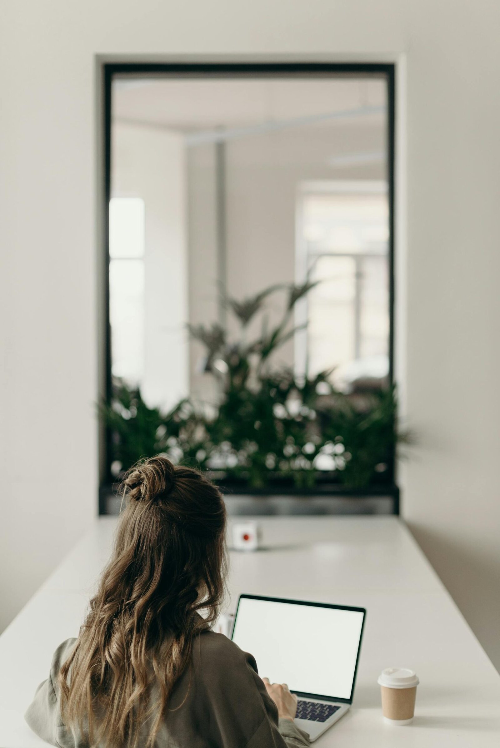 Girl using laptop on a table in a room with mirror on her morning job