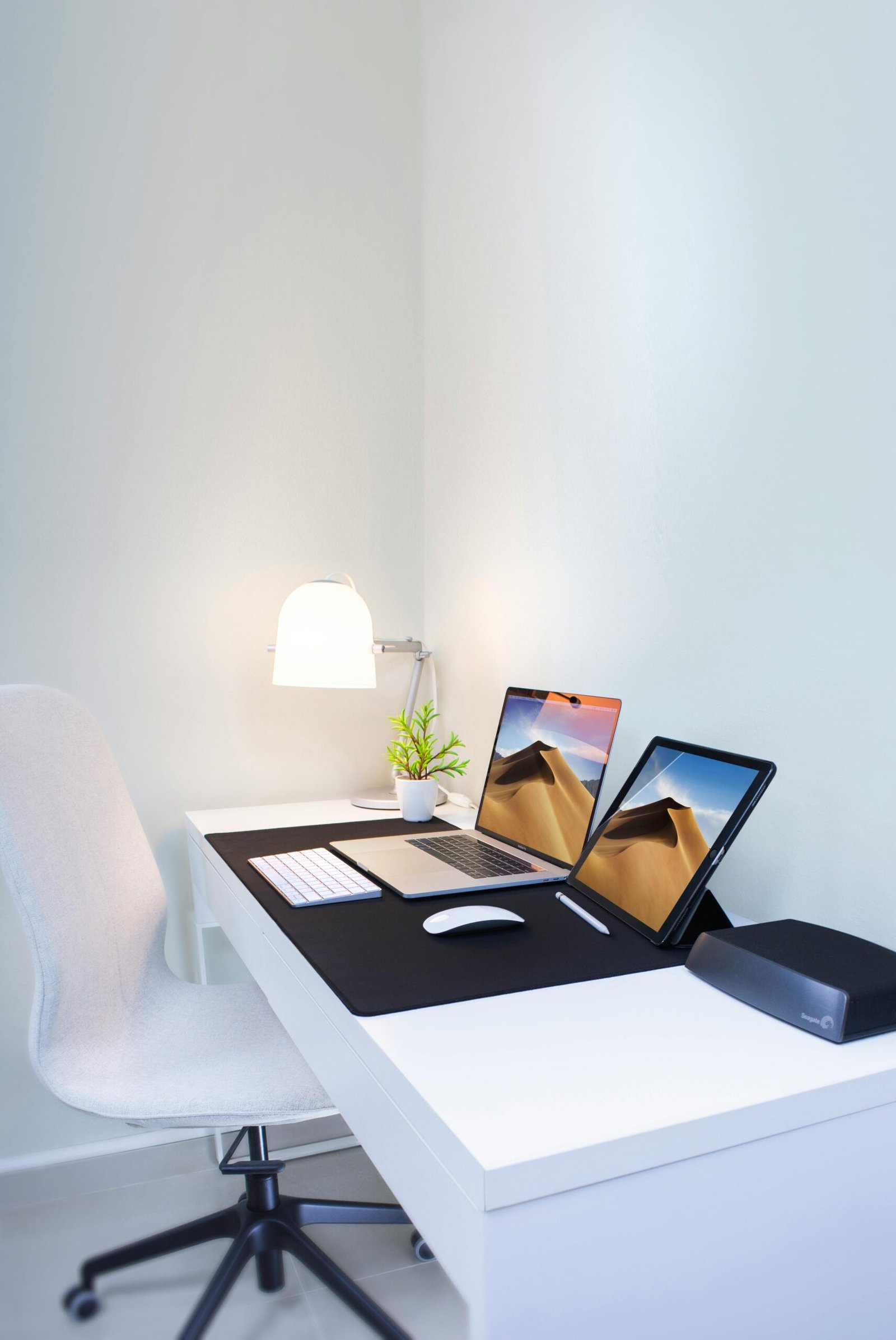 Two laptops displayed on the desk at office, with light focussing on them, at white background.