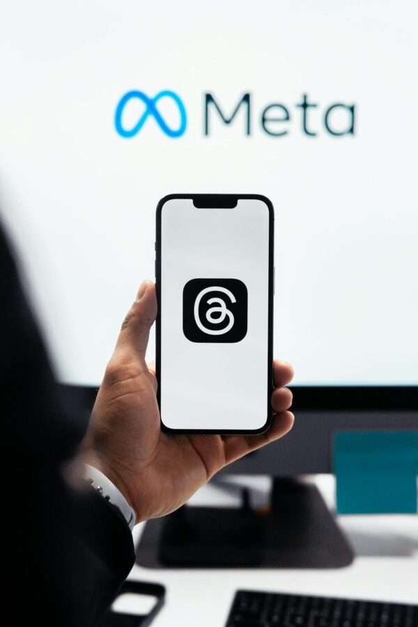 An employee in meeting at meta topic, holding his mobile in hand, displaying social platform threads.